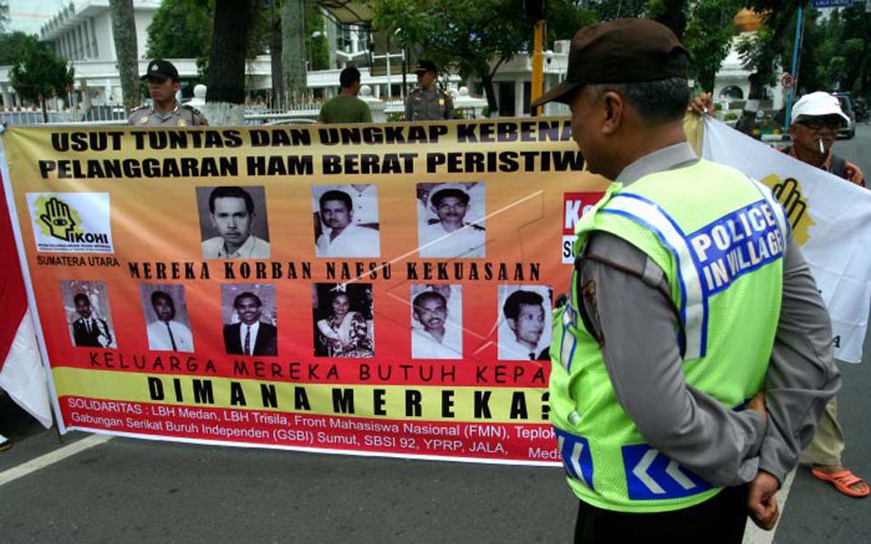 Police officer watches demonstration demanding justice for 1965 victims (Antara)