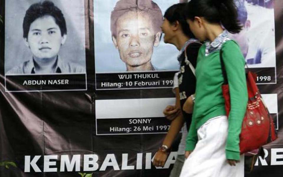 Woman walks past pictures of the 13 activists disappeared in 1997-98 (Tribune)