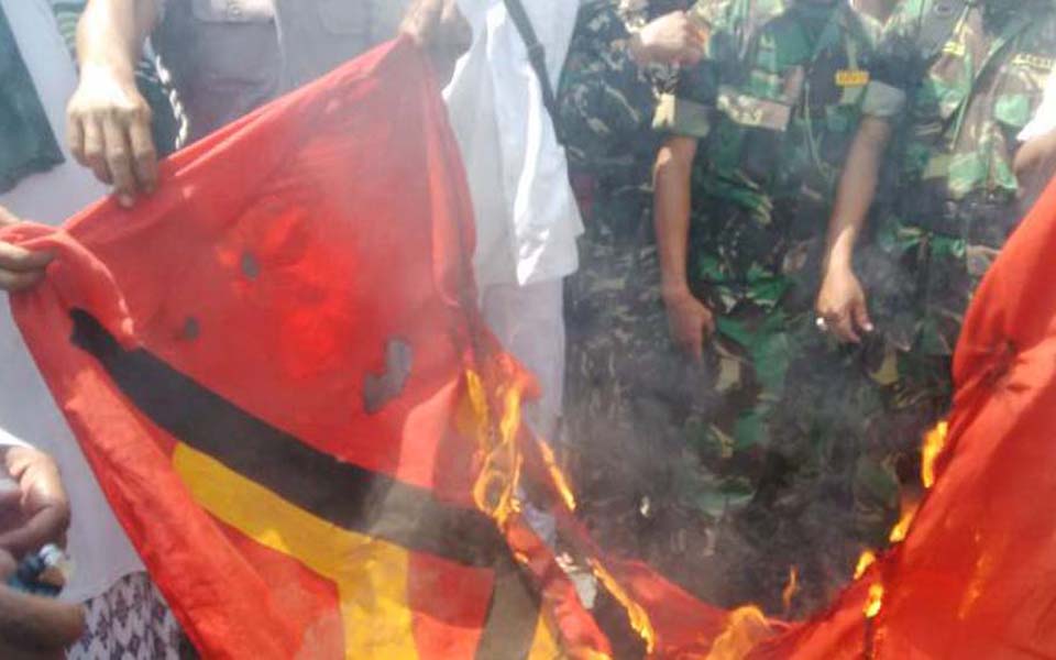 Soldiers watch as Islamic Defenders Front burn communist flag (Kompas)