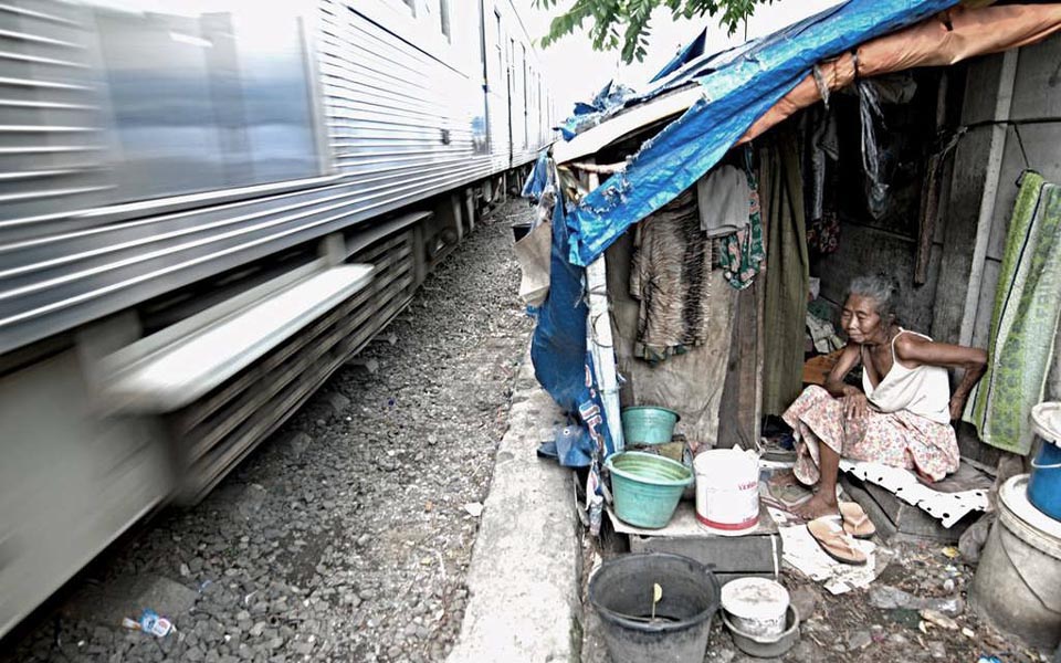 Train passes slum dwelling alongside railway tracks (Kata Data)
