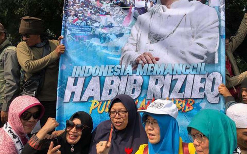 Fans pose for selfies in front of Rizieq Shihab banner – June 26, 2019 (CNN)