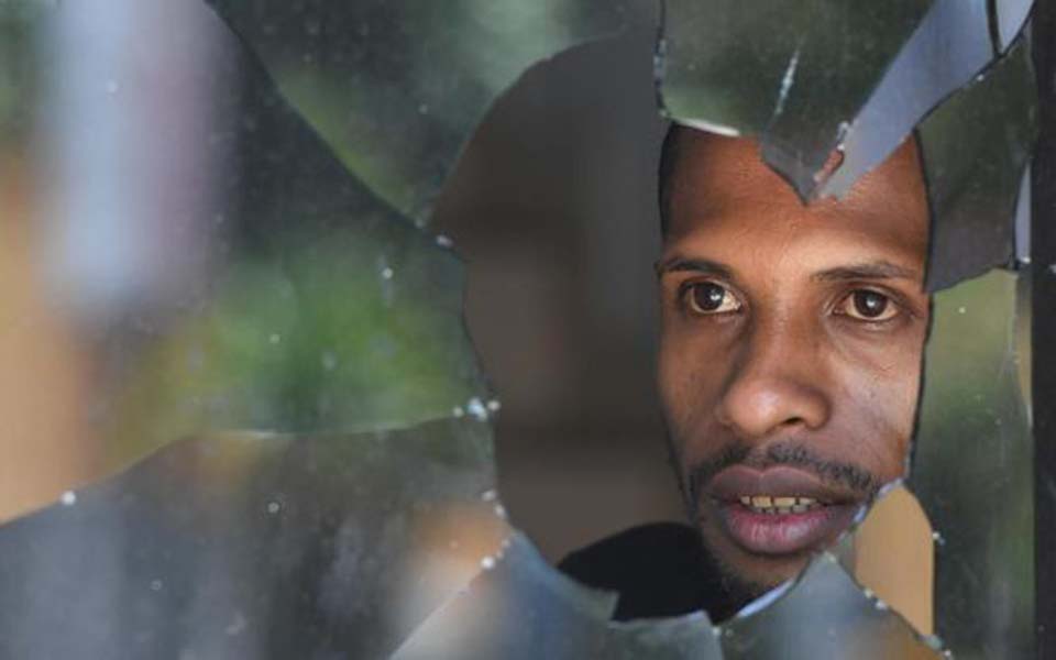 Papuan man looks through broken window in Jayapura – August 31, 2019 (Antara)