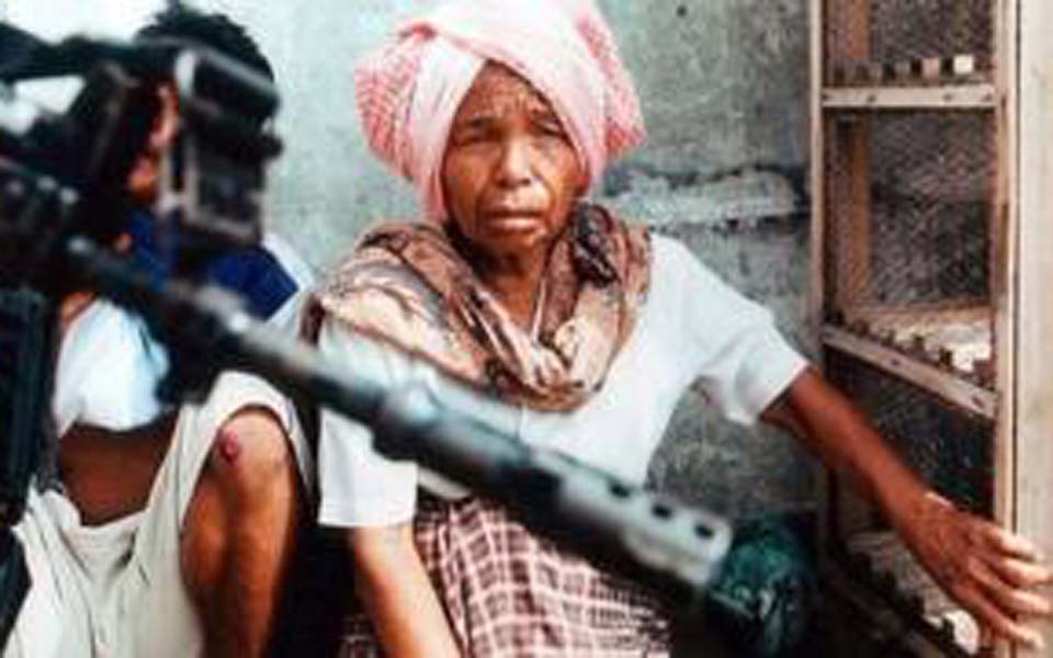 TNI solider stands in front of women in Lhokseumawe - May 25, 2003 (BBC)