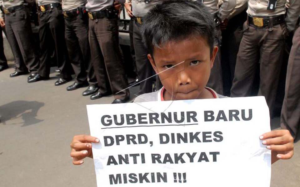 Protester holds banner at Urban Poor Union rally (Antara)