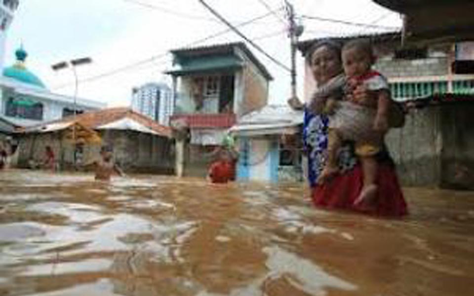 Mother carries baby through flood waters in Jakarta in 2007 (Sindo News)