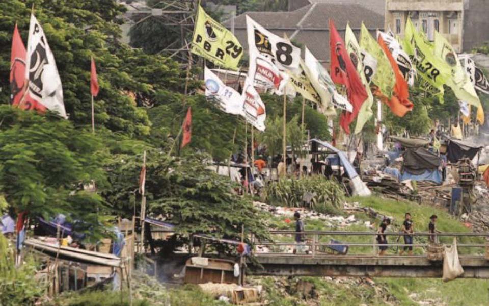 Political party flags fly over riverside community (Kompas)