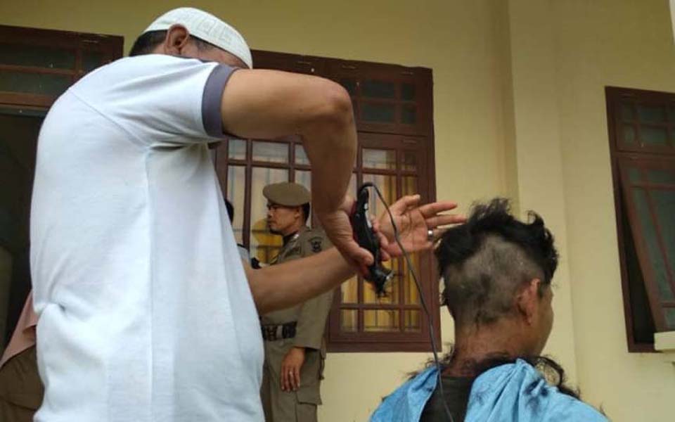 Religious police shaving the head of a transgender women (Kumparan)